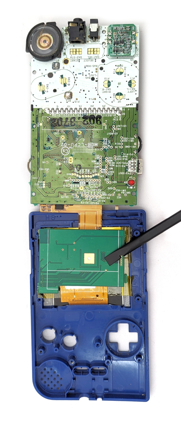 A game boy that has been opened up, exposing its circuitboard. The board has been folded over to show the back of the screen.