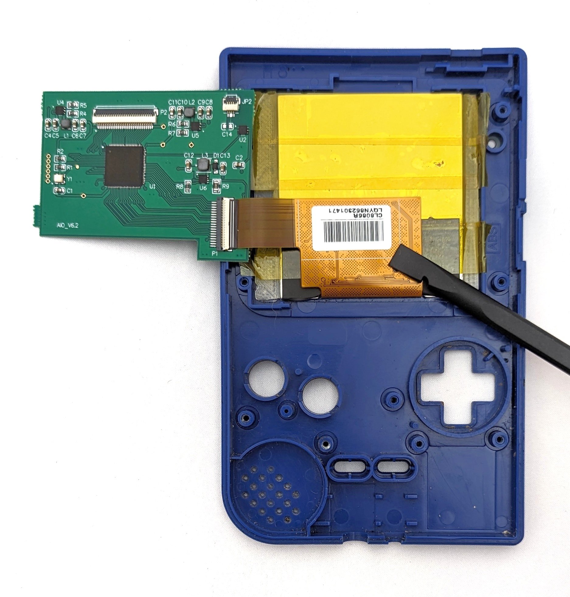 The inside shell of a game boy with a new screen implemented. A circuit board hangs off the side.