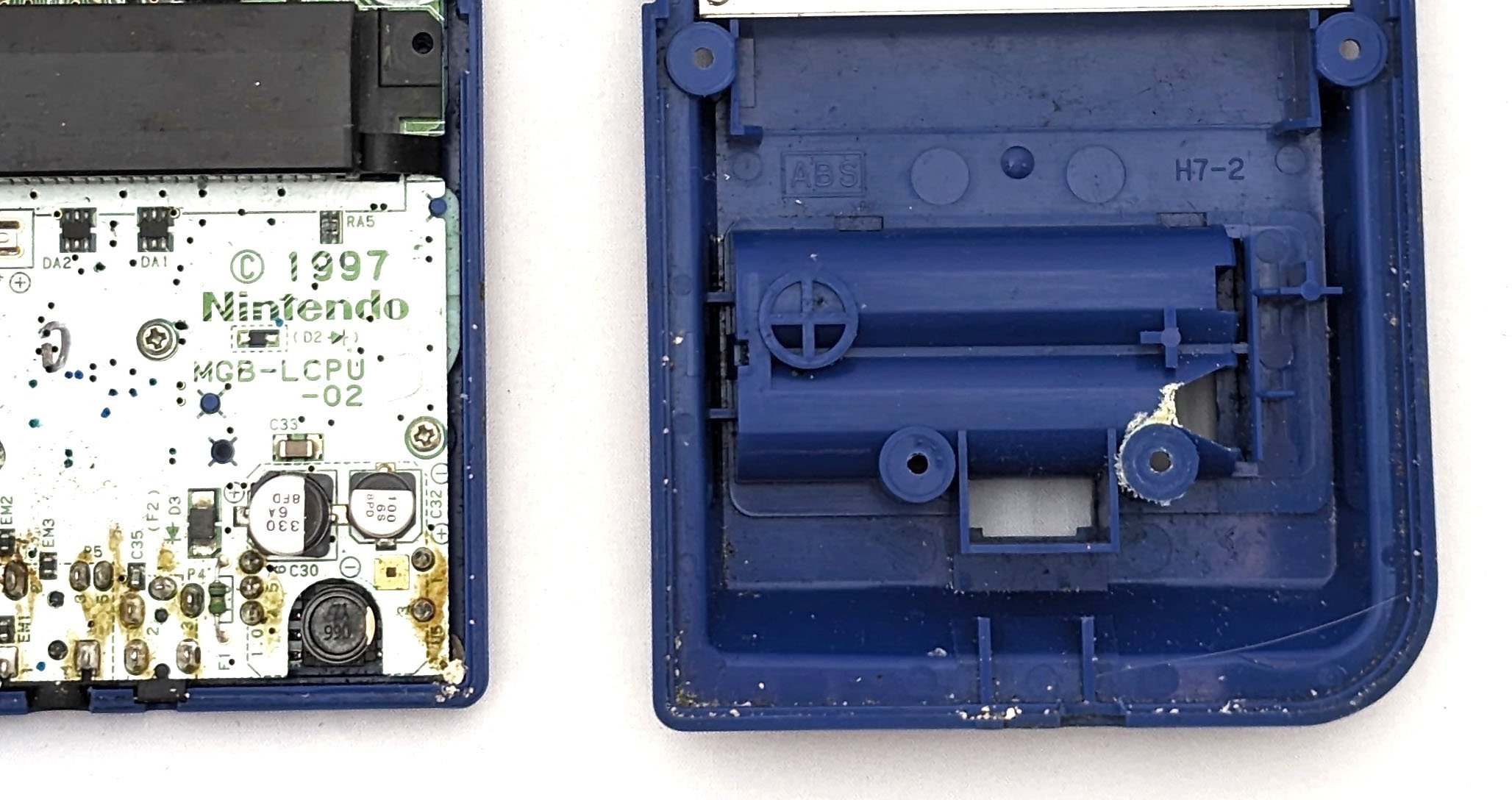 a close up on the inside of a game boy, with battery acid and yellow chemicals caked on.