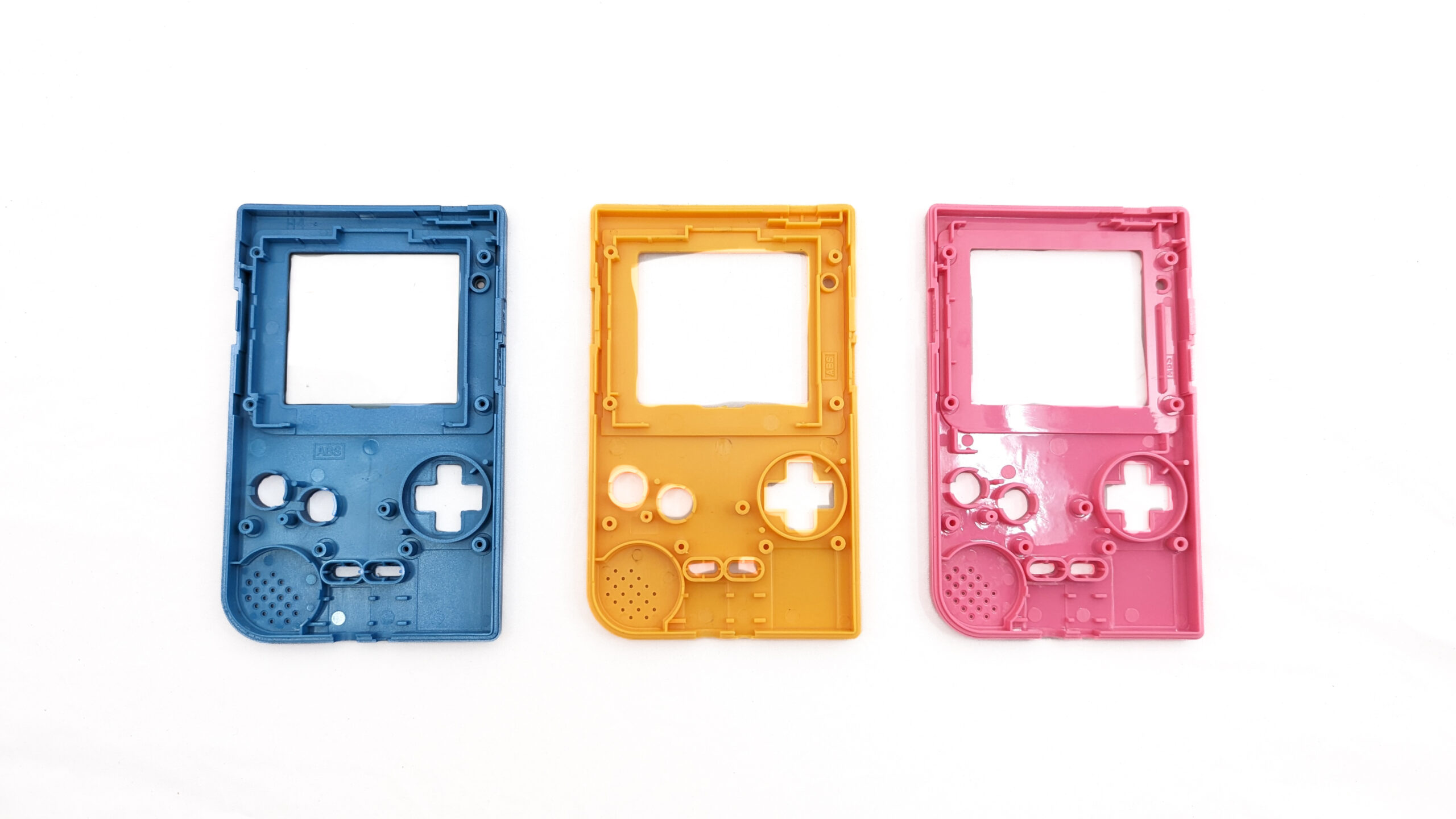 Three game boy shells in a row: blue, yellow, and pink.