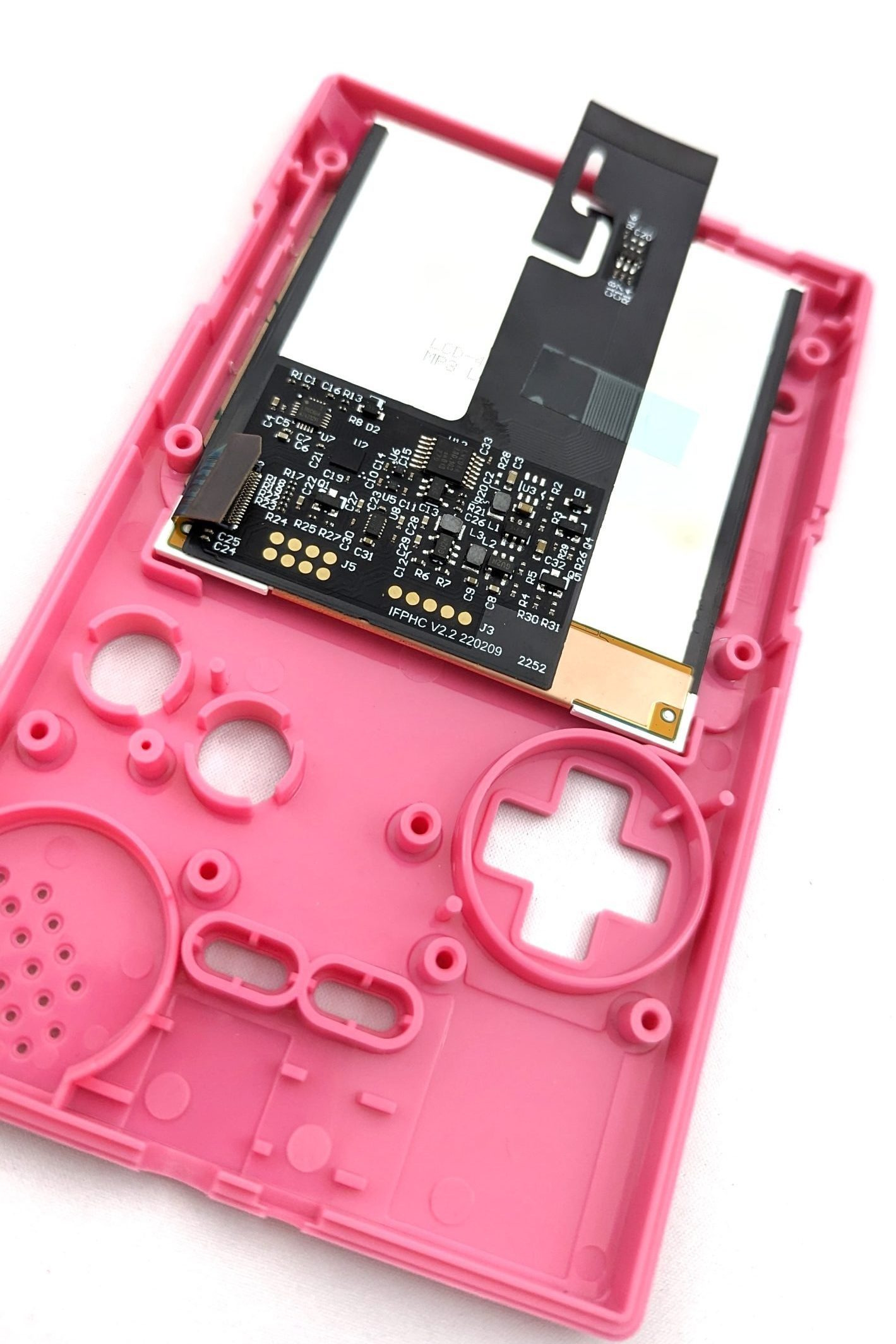 A new screen being inserted into the front of a pink game boy shell