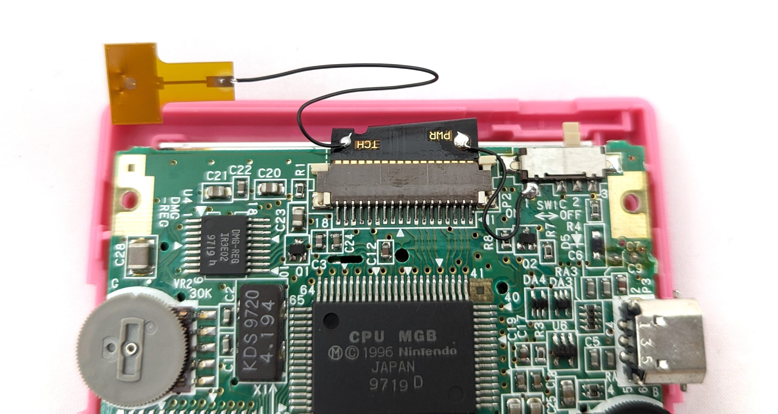 A close up on the top of the game boy critcuit board, with a touch sensor attached on a thin wire.